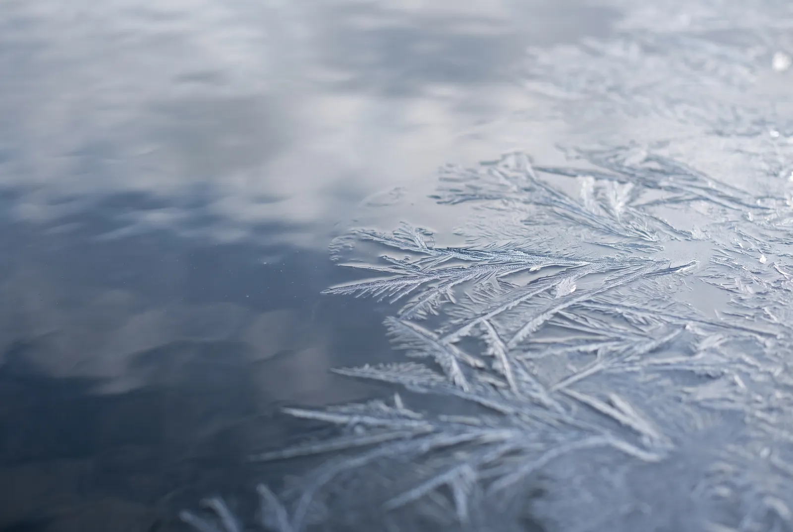 Ice crystals spreading across rippled water as it freezes